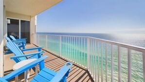 A balcony with blue chairs and a table, overlooking a clear ocean view. - Beach Blessing 2501-Ocean View-Sleeps 10 (Panama City Beach)