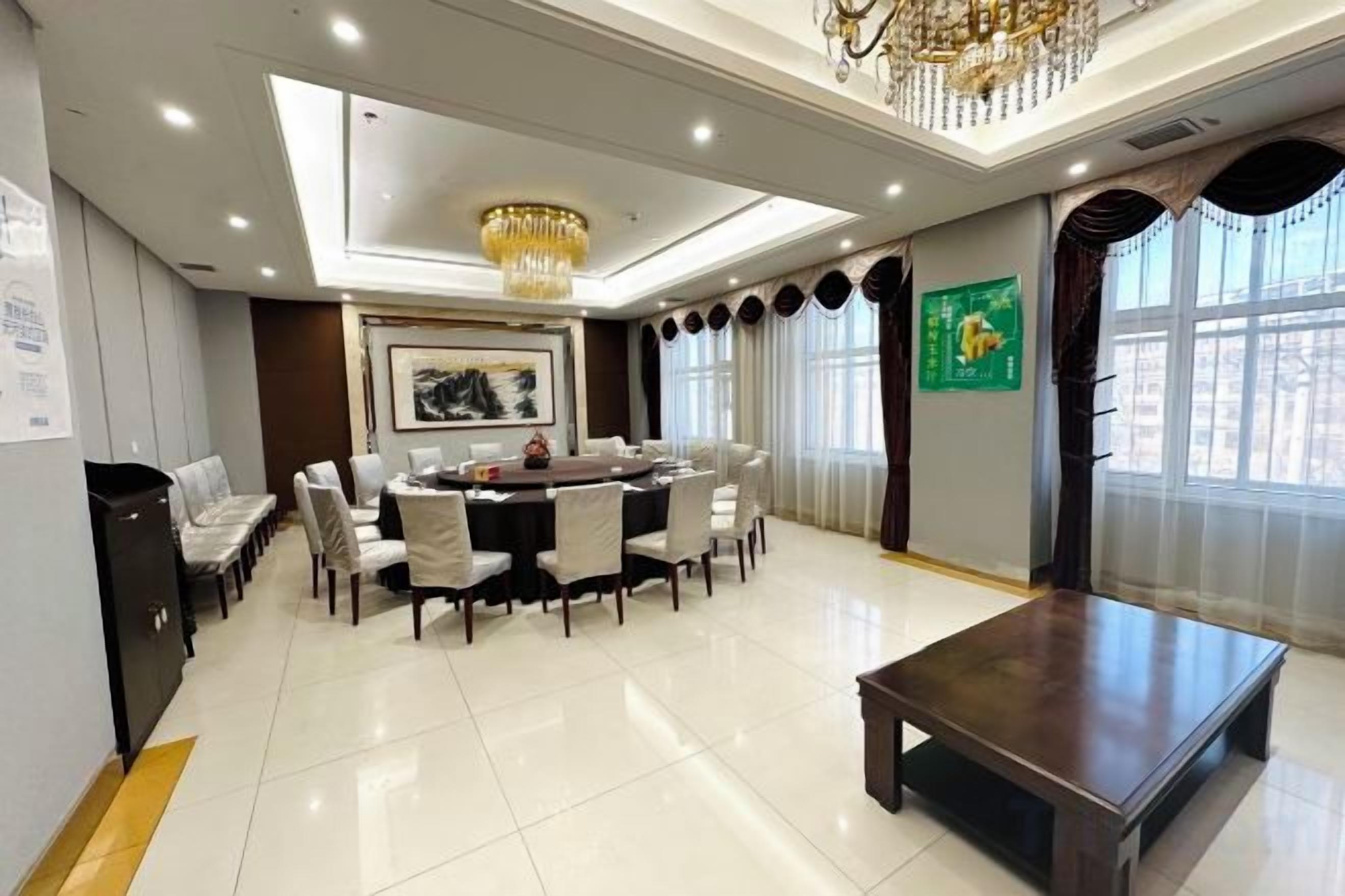 A spacious dining area with a round table, chairs, and a chandelier.