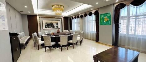 A spacious dining area with a round table, chairs, and a chandelier.