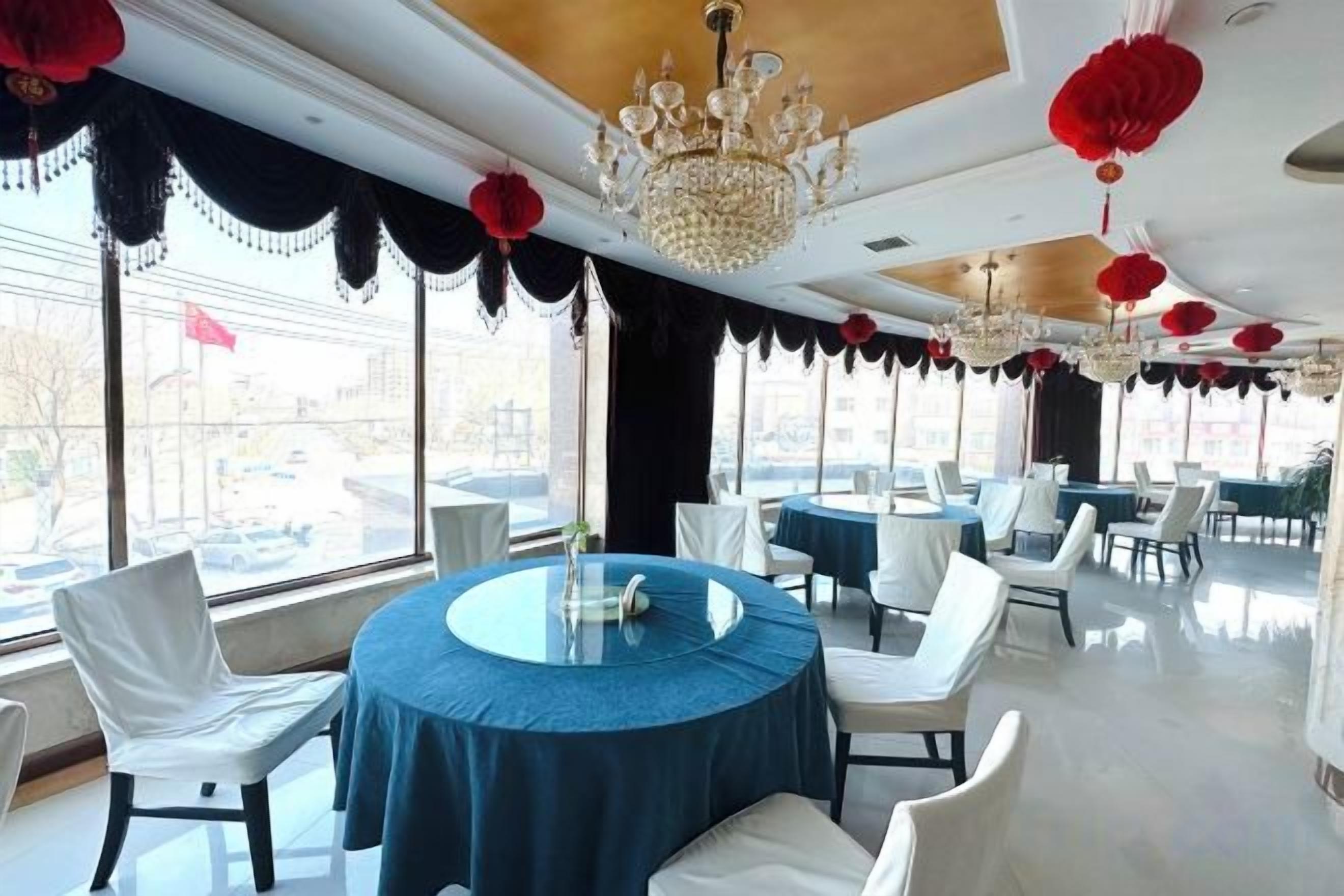 Un comedor con mesas redondas, sillas blancas y ventanas amplias.
