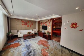 Un salon moderne avec un canapé, une table basse et un téléviseur, décoré d’objets rouges et agrémenté d’un tapis à motifs.