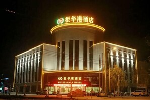 A hotel with a prominent circular sign, a large entrance with a red awning, and a modern architectural design.