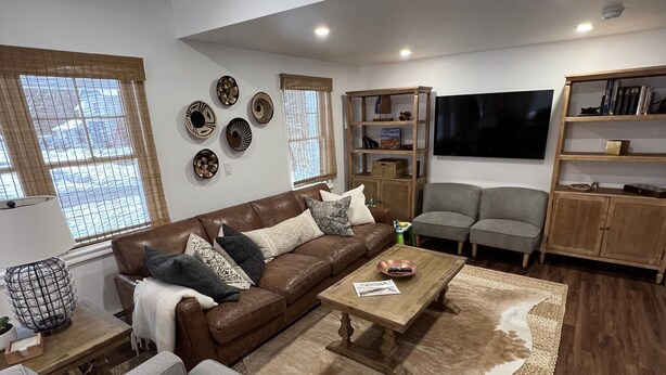 A modern living room with a brown leather sofa, a grey sofa, a wooden coffee table, and a large woven rug. - Wow! Only 3 min to Gore Mtn! King bed too (North Creek)