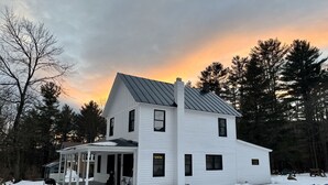 A two-story white house with a porch and a chimney. - Wow! Only 3 min to Gore Mtn! King bed too (North Creek)