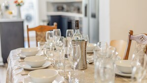 A dining table set with white plates, bowls, and clear glasses, with a decorative bottle centerpiece. - 6 bedroom accommodation in Ramsgate (Ramsgate)