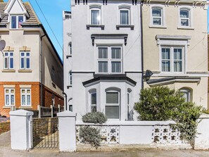 A multi-story building with a white facade, multiple windows, and a gated entrance. - 6 bedroom accommodation in Ramsgate (Ramsgate)