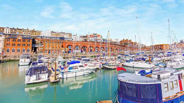 A marina with numerous boats docked, a historic building with arched windows, and a clear blue sky. - 6 bedroom accommodation in Ramsgate (Ramsgate)