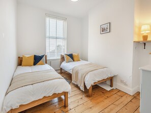 A bedroom with two wooden beds, white bedding, and a window with blinds. - 6 bedroom accommodation in Ramsgate (Ramsgate)