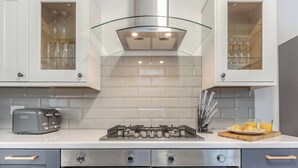 A modern kitchen with a gas stove, a toaster, and cabinets with glass doors. - 6 bedroom accommodation in Ramsgate (Ramsgate)