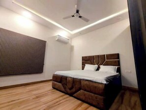 Une chambre à coucher au design moderne, dotée d’un lit avec une tête de lit en bois, d’un ventilateur de plafond et d’un appareil de climatisation.