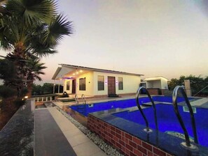 Un bâtiment moderne doté d’une piscine, d’un patio couvert et d’un palmier.