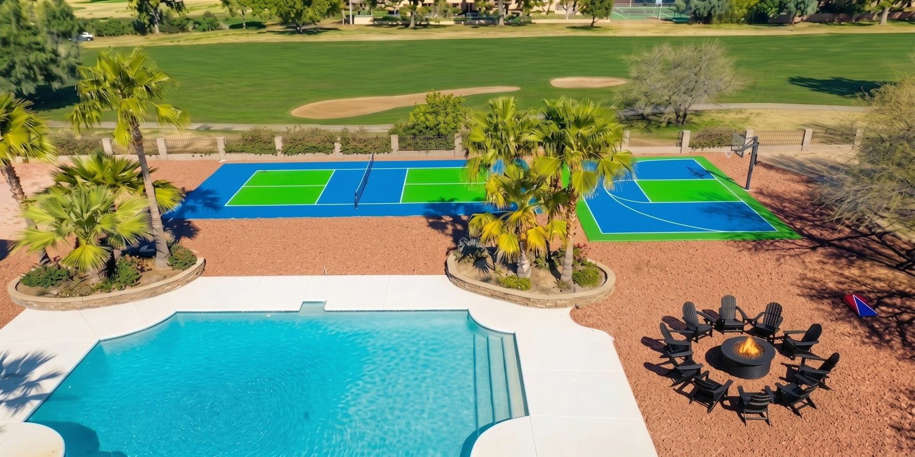 Piscina com lareira e espreguiçadeiras, rodeada por quadra de tênis e palmeiras.