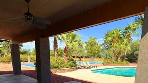 A hot tub with a view of a swimming pool and palm trees.