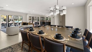 A modern dining area with a large round table set for a meal, surrounded by chairs.
