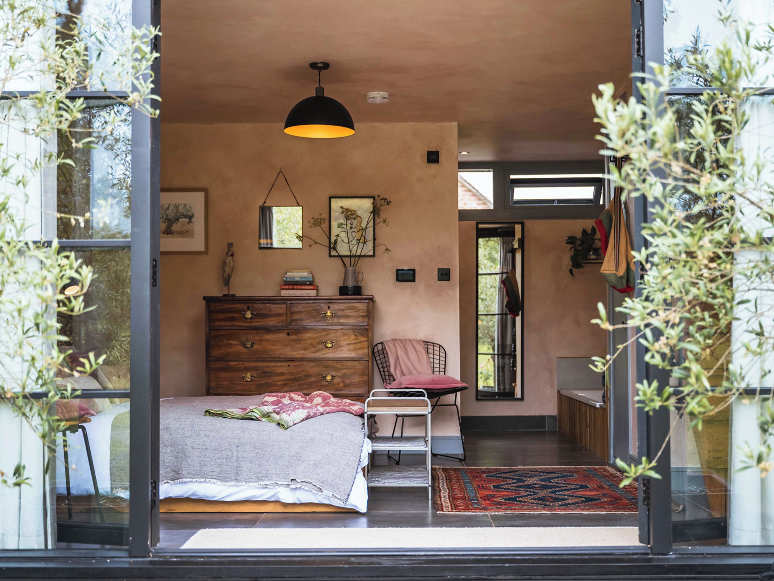 Un dormitorio con cama, cómoda, silla y lámpara colgante.