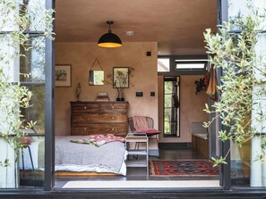 A bedroom with a bed, dresser, chair, and a hanging light fixture. - 1 bedroom accommodation in Willington, near Tarporley (Willington, near Tarporley)