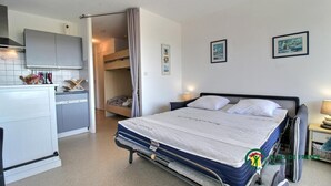 Ein kompaktes Hotelzimmer mit Bett, einer Küchenzeile und einem kleinen Badezimmer.