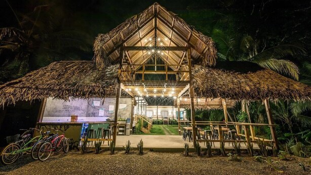 A thatched-roof structure with a wooden deck and seating area, surrounded by greenery. - Somewhere Bocas del Toro (Bocas del Toro)