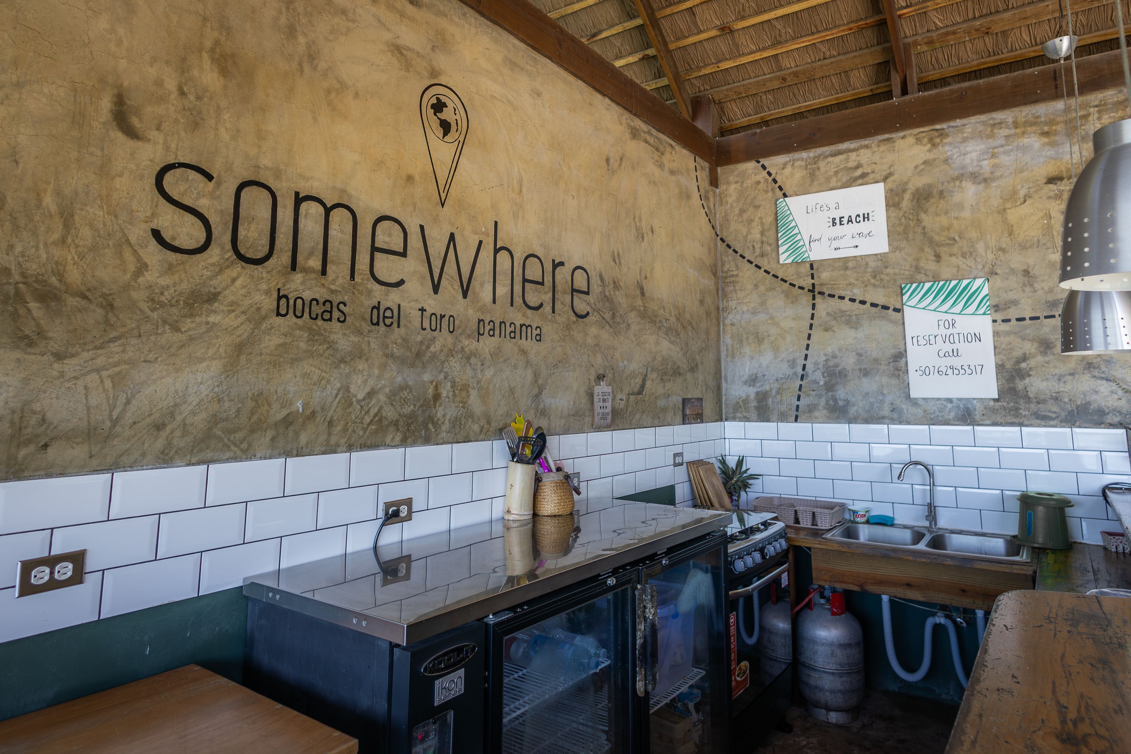 Eine Küche im rustikalen Stil, mit einem an der Wand befestigten Schild, das 'Somewhere' und 'Bocas del Toro Panama' zeigt.