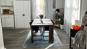 Ein Essbereich mit Holztisch und Stühlen, einer Kristallleuchtre und Blick auf die Küche.