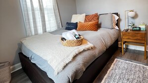 Ein Schlafzimmer mit Bett, Nachttisch, Lampe und einer kleinen Pflanze.
