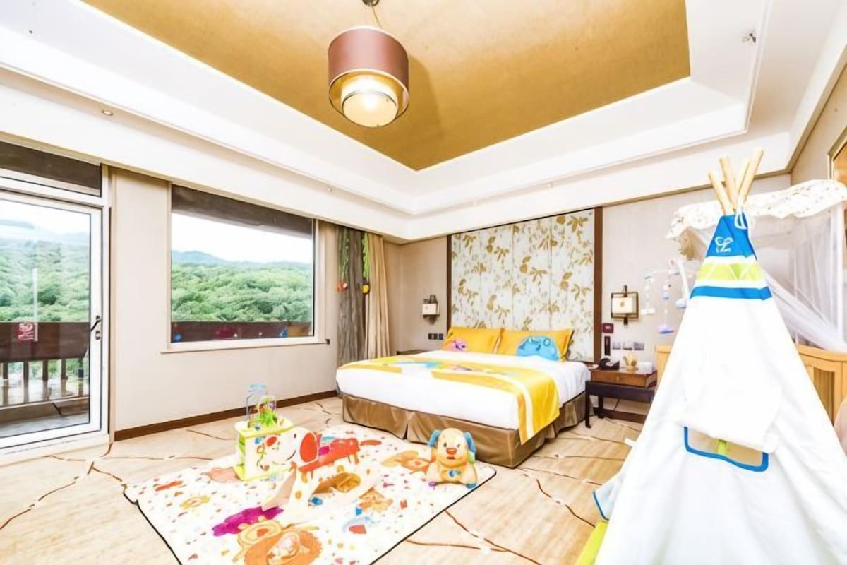Habitación de hotel con una cama grande, ventana con vistas, una estructura tipo tienda y una pequeña mesa con lámpara.