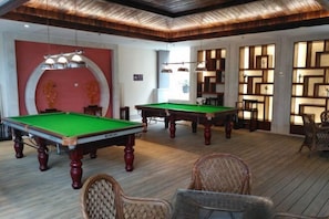 A billiards room with two pool tables, wicker chairs, and a wooden ceiling. - Dongquan Hot Spring Holiday Hotel (Dalian)