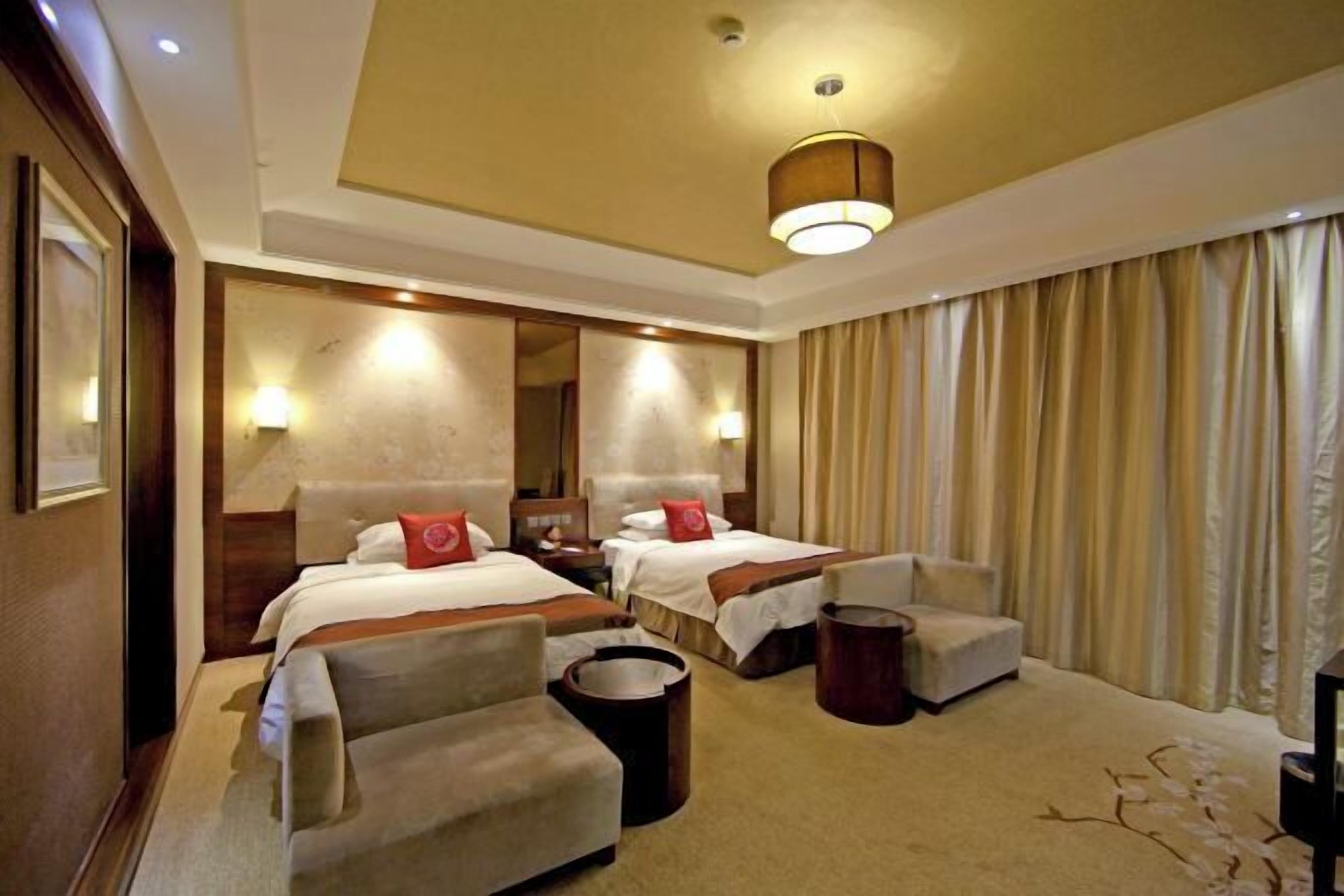 A hotel room with two beds, a sofa, a small table, and a television.