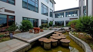 A modern building with a courtyard featuring a water feature and wooden stools. - Dongquan Hot Spring Holiday Hotel (Dalian)