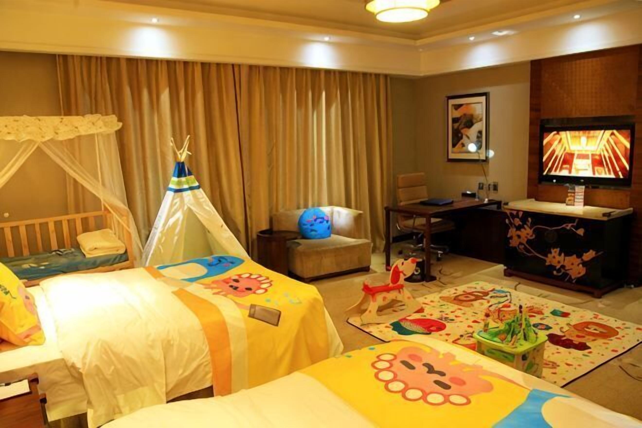 A hotel room with two beds, a TV, a desk, and a chair.