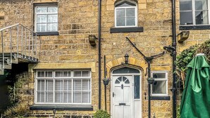 A two-story stone building with a white door, multiple windows, and a small staircase. - 3 bedroom accommodation in Utley, near Haworth (Utley, near Haworth)