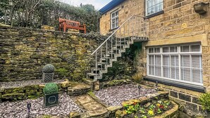 A stone building with a stone staircase leading to a wooden deck. - 3 bedroom accommodation in Utley, near Haworth (Utley, near Haworth)