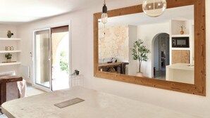 A modern interior with a large mirror, wooden beams, a stone wall, and a minimalist design.