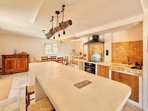 A modern kitchen with a large island, wooden cabinetry, and a stone backsplash. - Comfortable Cottage – Sleeps 15 – Panoramic Mountain View, Terrace, Hautes-Alpes (Embrun)
