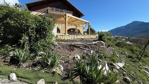 A wooden house with a stone foundation, a balcony, and a view of mountains.