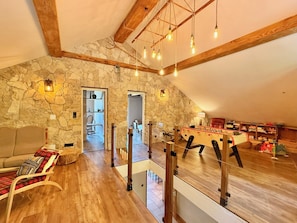 A spacious loft with a stone wall, wooden beams, a foosball table, and a cozy seating area. - Comfortable Cottage – Sleeps 15 – Panoramic Mountain View, Terrace, Hautes-Alpes (Embrun)