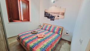 Une chambre à coucher avec un lit, une fenêtre, un tableau accroché au mur et une table de chevet.