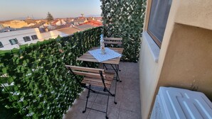 Un balcon agrémenté d’une table et de chaises, entouré d’un luxuriant feuillage.