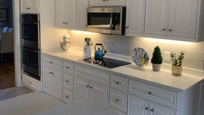 A modern kitchen with white cabinetry, stainless steel appliances, and a central island. - Master’s Rental - Golf course view in Woodside’s beautiful gated community! (Aiken)