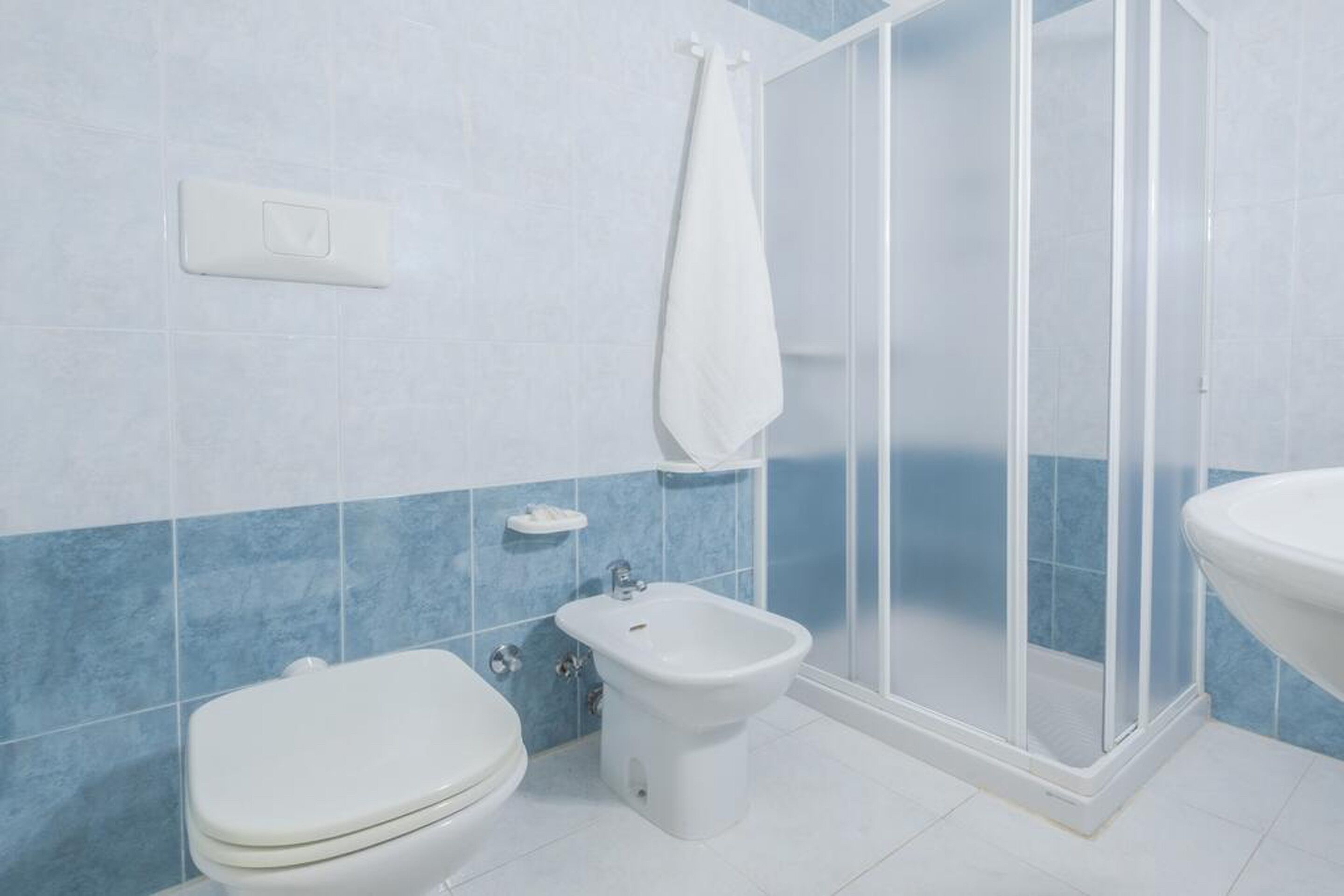 Un baño con inodoro, bidé y cabina de ducha.