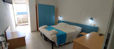 Ein Hotelzimmer mit Bett, Nachttischen, Schreibtisch, Stuhl und Kleiderschrank.