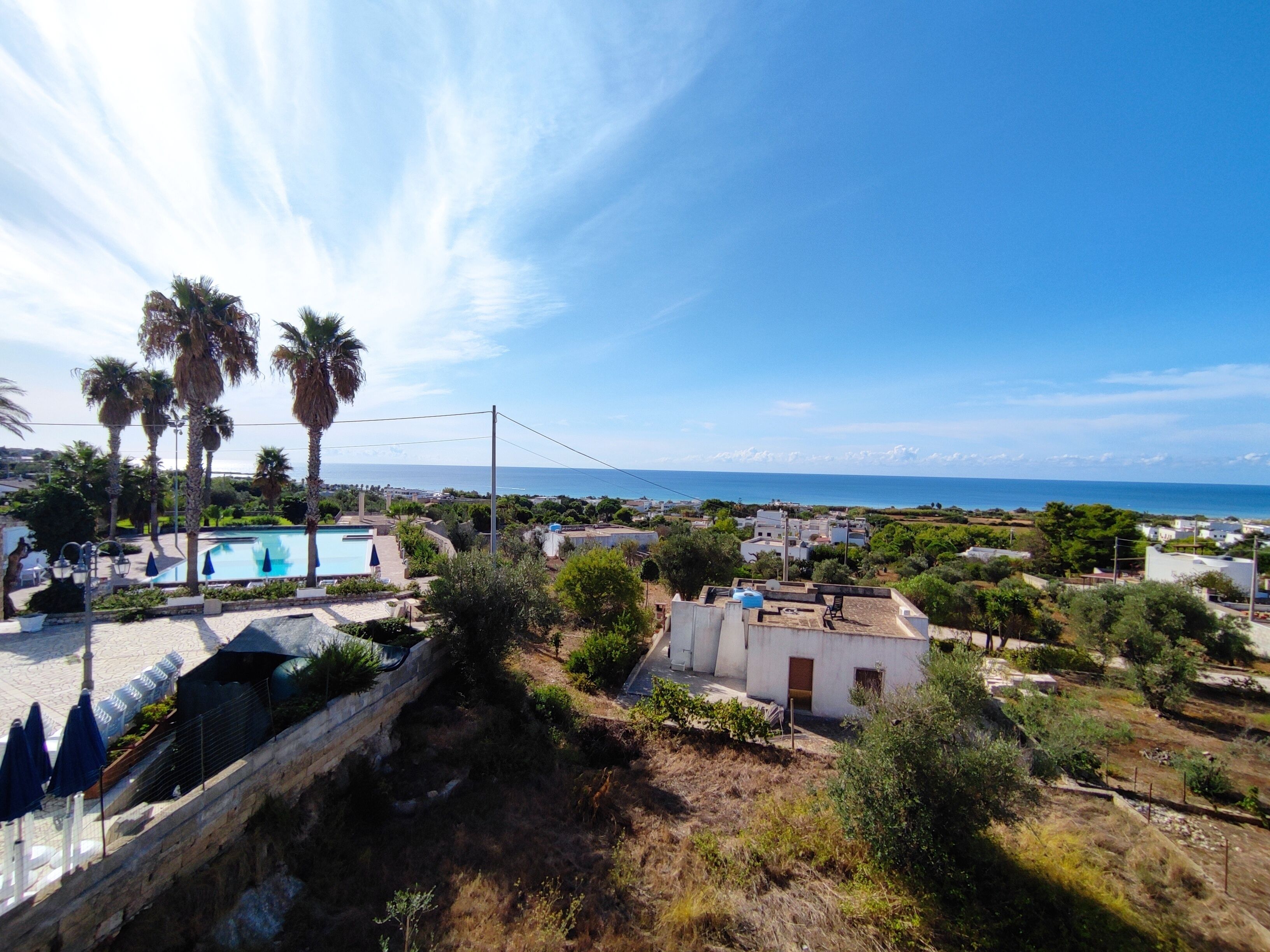 Un quartier résidentiel doté d’une piscine, de palmiers et offrant une vue sur la mer.