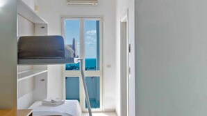 A hotel room with a bunk bed, a desk, and a view of the sea through a glass door. - Picchio Hotel Pescoluse (Salve)