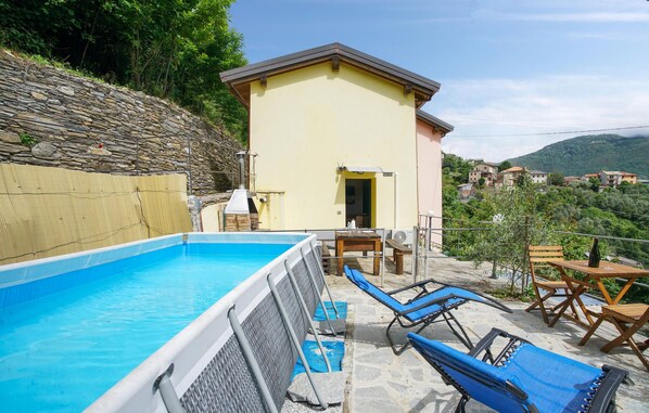 A pool area with a stone wall, a small building, and a view of a village in the background.