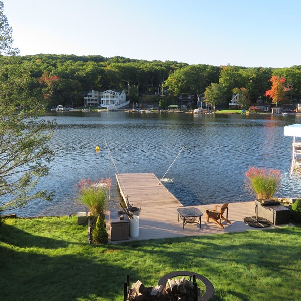 A lakeside dock with a fishing rod, a fire pit, and outdoor seating.