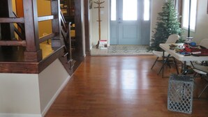 Amplia sala de estar con una escalera de madera, un comedor con mesa y sillas, y un árbol de Navidad.
