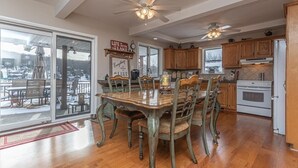 Una cocina amplia con gabinetes de madera, una mesa de comedor con sillas y vistas al exterior a través de grandes puertas corredizas de vidrio.