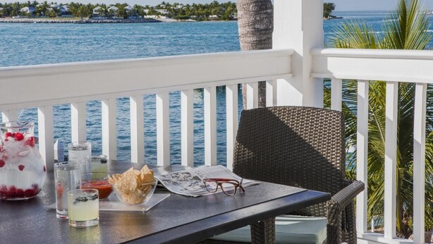 A table with a drink, a basket, and a newspaper on a balcony overlooking the sea. - DOWNTOWN KEY WEST 2BED OCEANFRONT! (Key West)