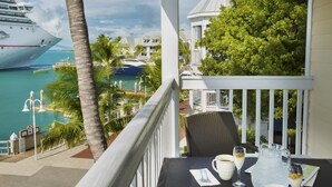 A balcony with a table set for two, overlooking a marina with boats and a pool. - DOWNTOWN KEY WEST 2BED OCEANFRONT! (Key West)