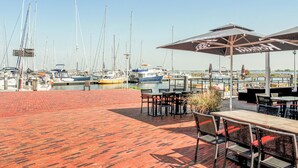 A marina with boats docked, outdoor seating with umbrellas, and a brick patio. - Stunning apartment in Bruinisse (Bruinisse)